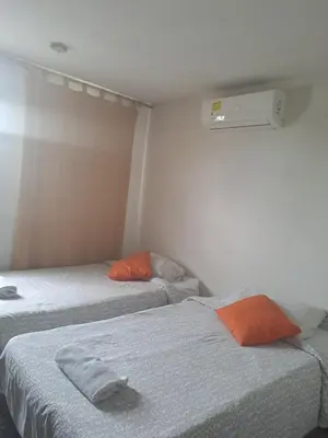 a room with two beds and an orange pillow at B&B Grand Royal Inn in Barranquilla