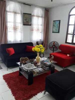 a living room with a black couch and red furniture at B&B Grand Royal Inn in Barranquilla