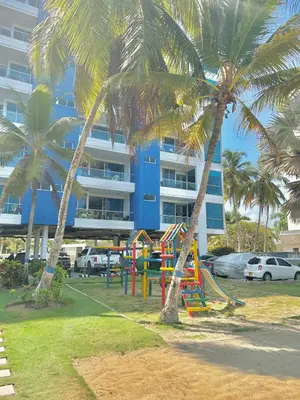 two palm trees with a playground in front of a building at Apartamento con vista al mar en Coveñas in Coveñas