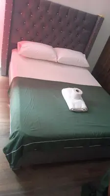 a bed with a green sheet and a roll of toilet paper on it at AQUALINASTAR in Cartagena de Indias