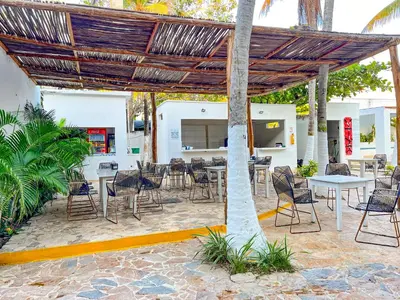 a patio with tables and chairs under a pergola at Hotel Palma Grande by Stanza in Coveñas