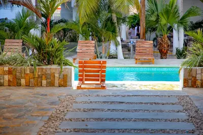 three chairs sitting next to a swimming pool at Hotel Palma Grande by Stanza in Coveñas