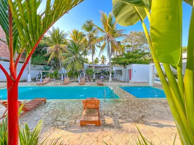 a resort pool with a chair and palm trees at Hotel Palma Grande by Stanza in Coveñas