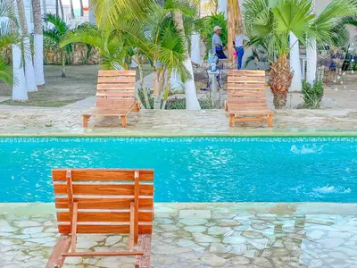 three wooden chairs sitting next to a swimming pool at Hotel Palma Grande by Stanza in Coveñas