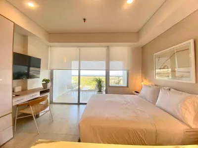 a bedroom with a bed and a desk and a television at Wynwood Cartagena Beach in Cartagena de Indias