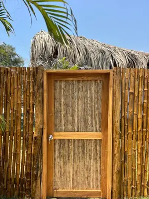 a wooden gate with a thatch roof on top of a fence at JERUSALEMA BEACH GLAMPING in Tolú