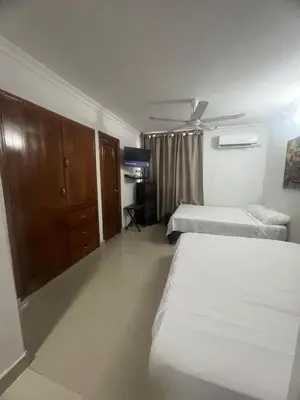 a bedroom with two beds and a cabinet and a tv at A un paso del mar in Cartagena de Indias