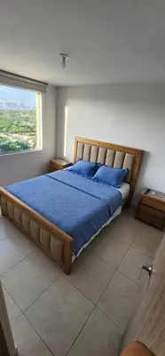a bedroom with a bed with blue sheets and a window at Espectacular apartamento piso 14 al norte de Barranquilla in Barranquilla