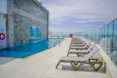 a row of lounge chairs next to a swimming pool at Apartament Bocagrande Palmetto Beach Front 3204 in Cartagena de Indias