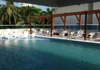 a swimming pool with white lounge chairs and the water at Confort en la zona del Laguito in Cartagena de Indias