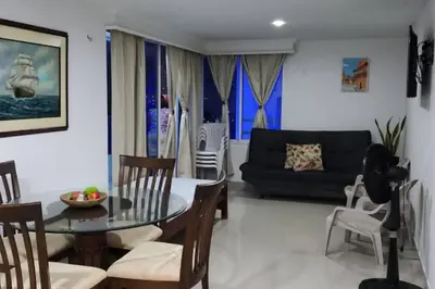 a dining room and living room with a glass table and chairs at Confort en la zona del Laguito in Cartagena de Indias