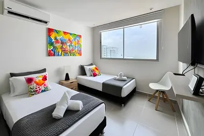 a bedroom with two beds and a desk and a window at Apartamento 2 dormitorios Morros Vistas. Piscina in Cartagena de Indias