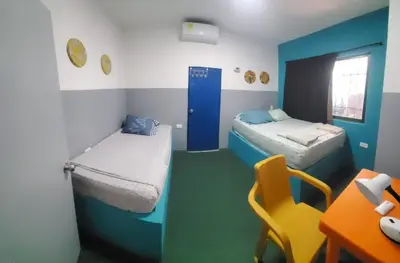 a room with two beds and a desk and a table at Hotelito La Aventura, AC private WC rooms near the old town, no tax in Cartagena de Indias