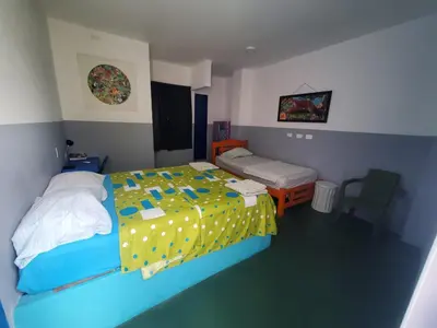 a bedroom with a bed with a yellow and blue comforter at Hotelito La Aventura, AC private WC rooms near the old town, no tax in Cartagena de Indias