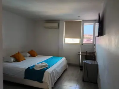 a small bedroom with a bed and a window at Hotel Doral Barranquilla in Barranquilla