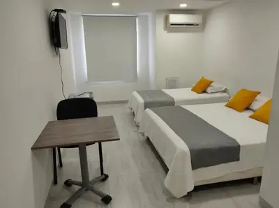 a room with two beds and a table and a desk at Hotel Doral Barranquilla in Barranquilla