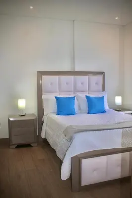 a bedroom with a large bed with blue pillows at Apartamento nuevo en cartagena en el cabrero in Cartagena de Indias