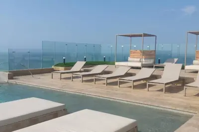 a group of white lounge chairs next to a swimming pool at Apartamento nuevo en cartagena en el cabrero in Cartagena de Indias
