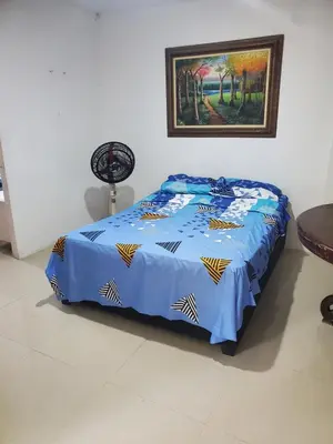 a bed with a blue comforter in a room at Apartamentos y habitaciones cerca a marbella in Cartagena de Indias