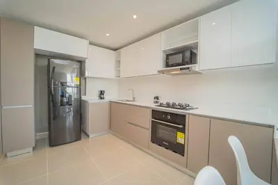 a kitchen with white cabinets and a stainless steel refrigerator at 1H Encanto Rentals @ Sunno Beach in Cartagena de Indias