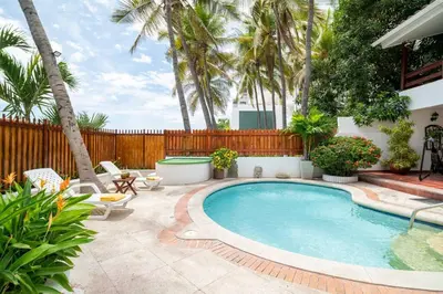 a swimming pool in a backyard with palm trees at El Refugio Beach House, Bello Horizonte, Santa Marta in Playa Dormida