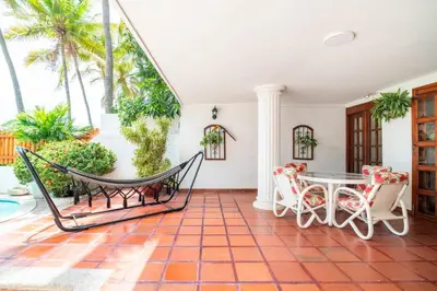 a porch with a hammock and a table and chairs at El Refugio Beach House, Bello Horizonte, Santa Marta in Playa Dormida