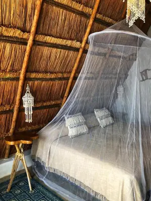 a bedroom with a bed in a straw roof at Namaste Beach Club & Hotel in Tierra Bomba