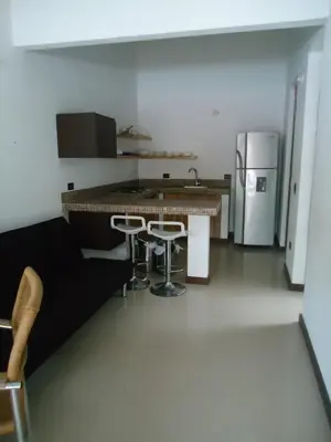 a kitchen with a counter and stools and a refrigerator at Cabañas La Española in Coveñas
