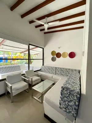 a living room with couches and tables and windows at Cabañas La Española in Coveñas