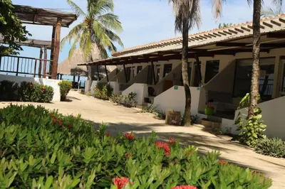 a house with palm trees and flowers in front of it at Cabañas La Española in Coveñas