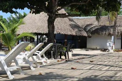 a group of chairs and tables and a thatched building at Cabañas La Española in Coveñas