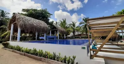 a resort with a swimming pool and a hut at Cabañas La Española in Coveñas