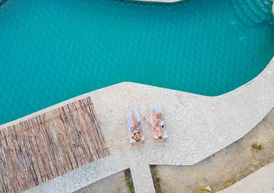 two people sitting on chairs next to a swimming pool at Coral De Fuego Isla Fuerte in Isla Fuerte
