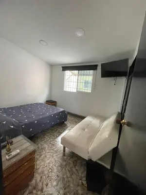a bedroom with a bed and a couch and a window at La casa de flor in Cartagena de Indias