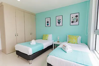 two beds in a room with blue walls at U-GO Palmetto Beach - Lujo Frente al Mar in Cartagena de Indias