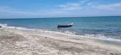 a boat sitting in the water on a beach at Apartamento Dorado Sunset in Santa Marta