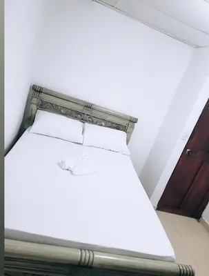 a white bed in a room with a wooden door at Rosymar in Cartagena de Indias
