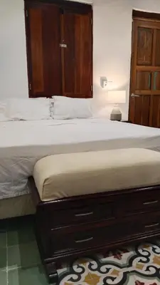 a bedroom with a large bed with a wooden cabinet at Casa Belia in Cartagena de Indias