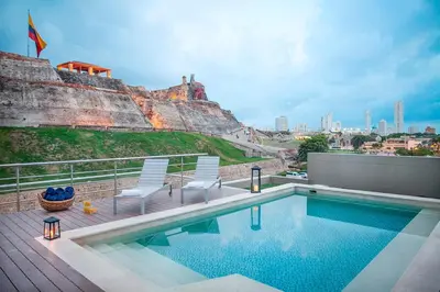 a swimming pool with two chairs and a castle at GHL San Lazaro Art Hotel in Cartagena de Indias