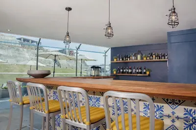 a bar with white chairs and a wooden counter at GHL San Lazaro Art Hotel in Cartagena de Indias