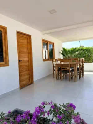 a dining room with a table and chairs and purple flowers at Mykonos Beach House Apartamentos By Jerusalema in Tolú