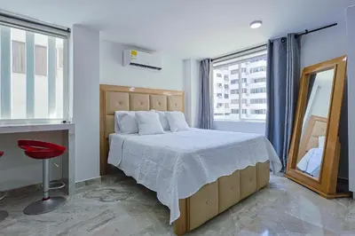 a bedroom with a large bed and a mirror at Lujoso Apartamento con salida a la playa in Cartagena de Indias