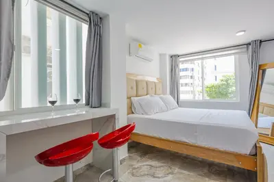 a bedroom with a bed and two red chairs at Lujoso Apartamento con salida a la playa in Cartagena de Indias