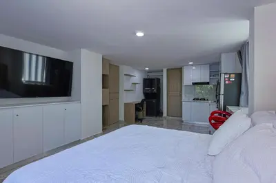 a bedroom with a white bed with a flat screen tv at Lujoso Apartamento con salida a la playa in Cartagena de Indias