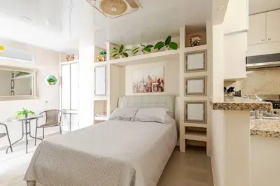 a white bedroom with a bed and a kitchen at Studio at the Resort Residence 2 in Puerto Colombia