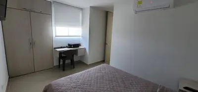 a bedroom with a bed and a desk and a window at Urbis 48 - Piso 23 in Cartagena de Indias