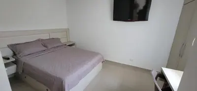 a small bedroom with a bed and a television at Urbis 48 - Piso 23 in Cartagena de Indias