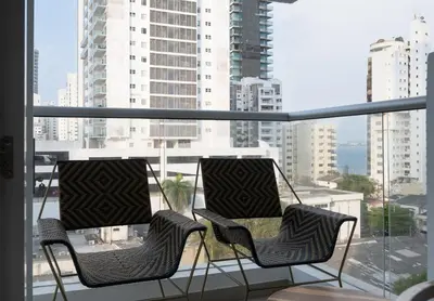 two chairs on a balcony with a view of a city at Luxury Apartment In Bocagrande With Ocean View 502 in Cartagena de Indias