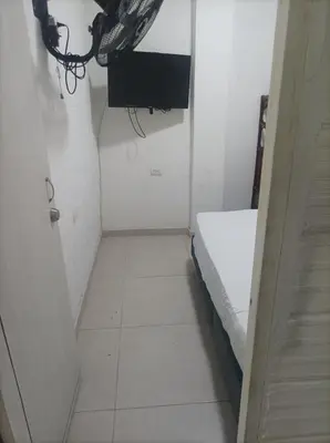 a small white room with a bed and a window at Hostal Catalleya in Cartagena de Indias