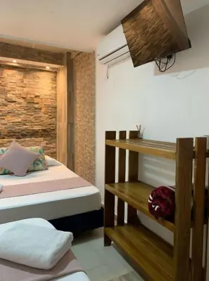 a bedroom with two beds and a brick wall at Hostal Catalleya in Cartagena de Indias